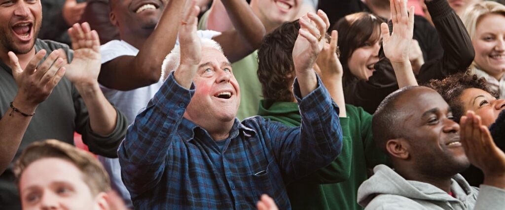 Picture of a man cheering in a crowd symbolizing a customer orientated workforce as a brand value at GOLDBECK SOLAR.